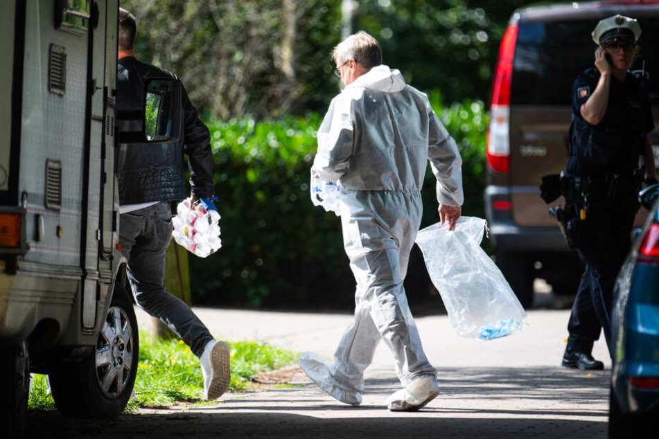 Polizisten und Beamte der Spurensicherung gehen zu dem Wohnhaus, in dem die Leiche der Frau gefunden wurde.