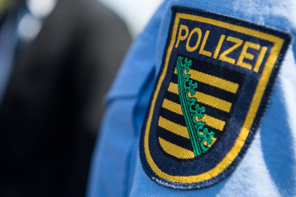Logo der sächsischen Polizei ist an einem Polizeiuniform angebracht.