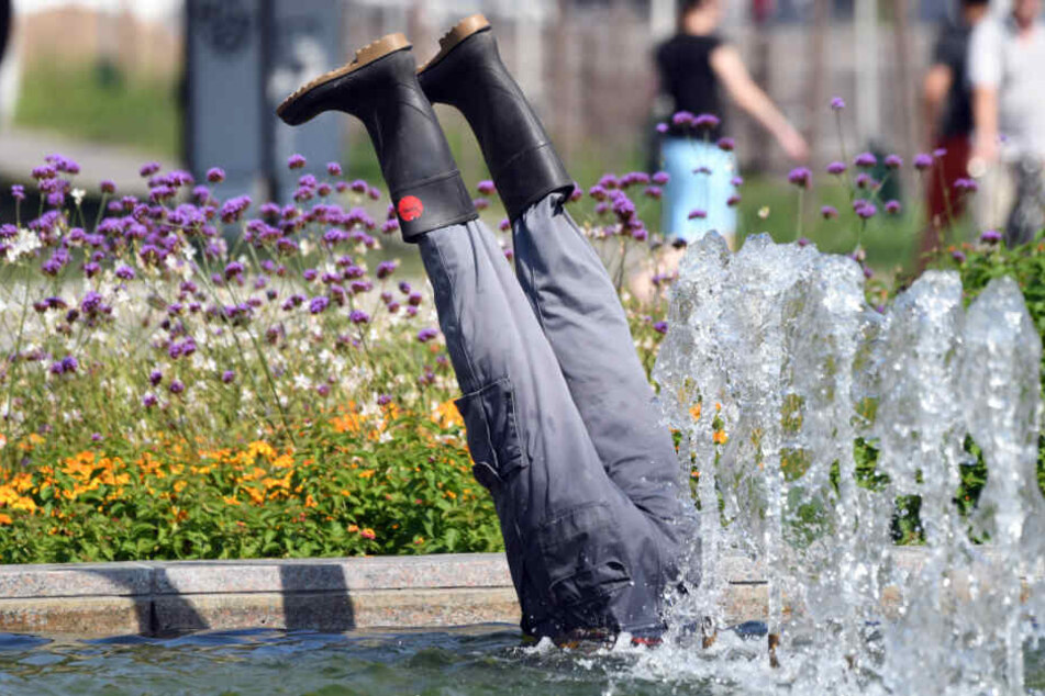 Aus einem Brunnen ragen zwei Beine mit Gummistiefeln.