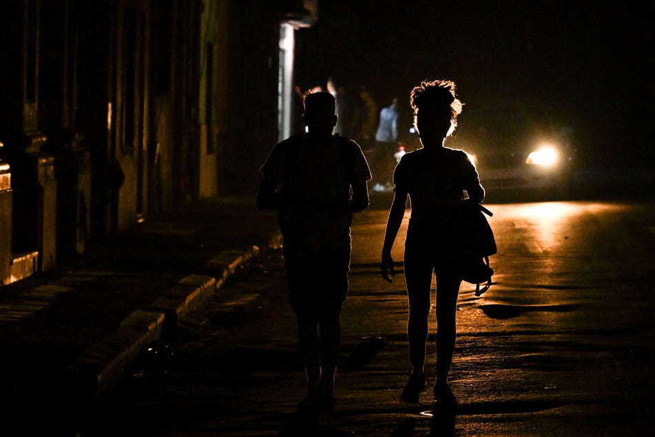 People walk down a dark street during a blackout in Havana, Cuba, on March 4, 2026.