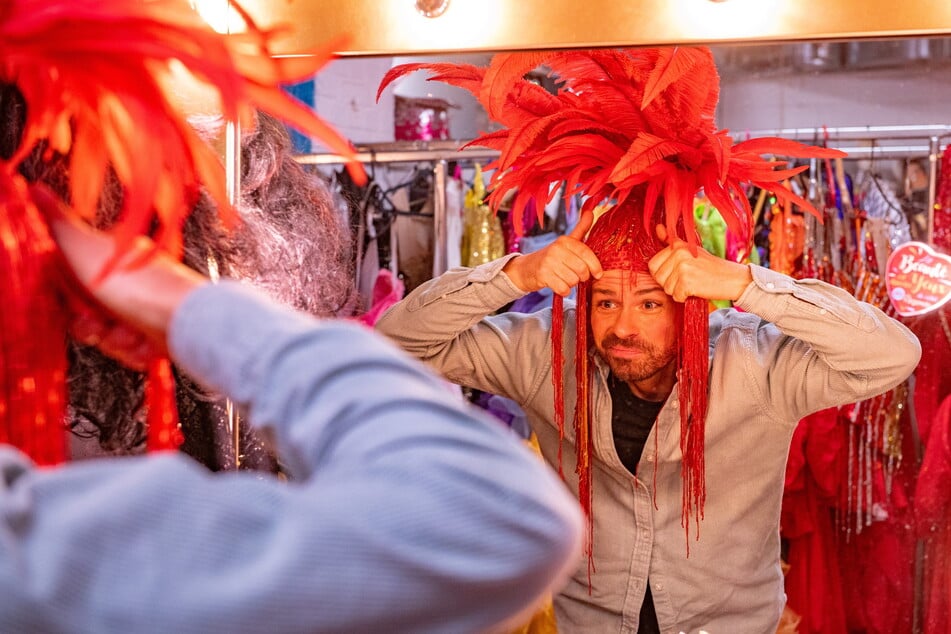 In der Theatergarderobe des "Carte Blanche" stülpt sich Christian einen glamourösen Kopfputz über.