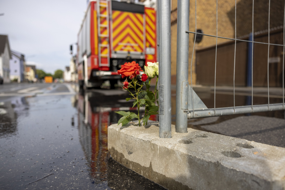 Blumen erinnern in Sankt Augustin an das verheerende Feuer in einem Motorradladen, bei dem zwei Feuerwehrleute den Tod fanden.