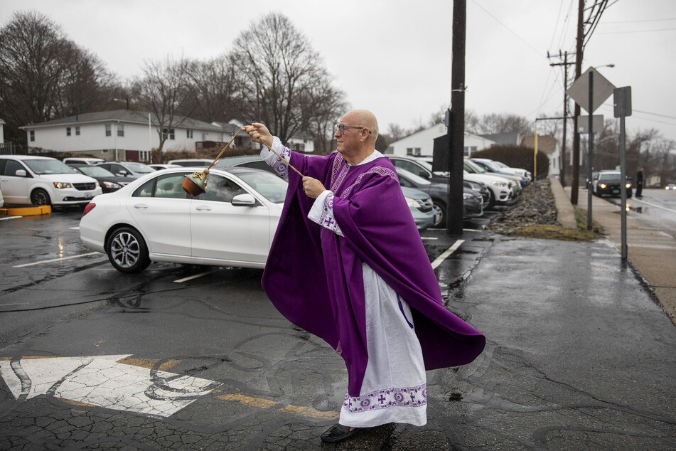 Pfarrer Peter Gower steht auf einem Parkplatz vor der katholischen Kirche "Our Lady of Grace" und verteilt Weihrauch vor Gläubigen, die die Messe in ihren Autos verfolgt haben.
