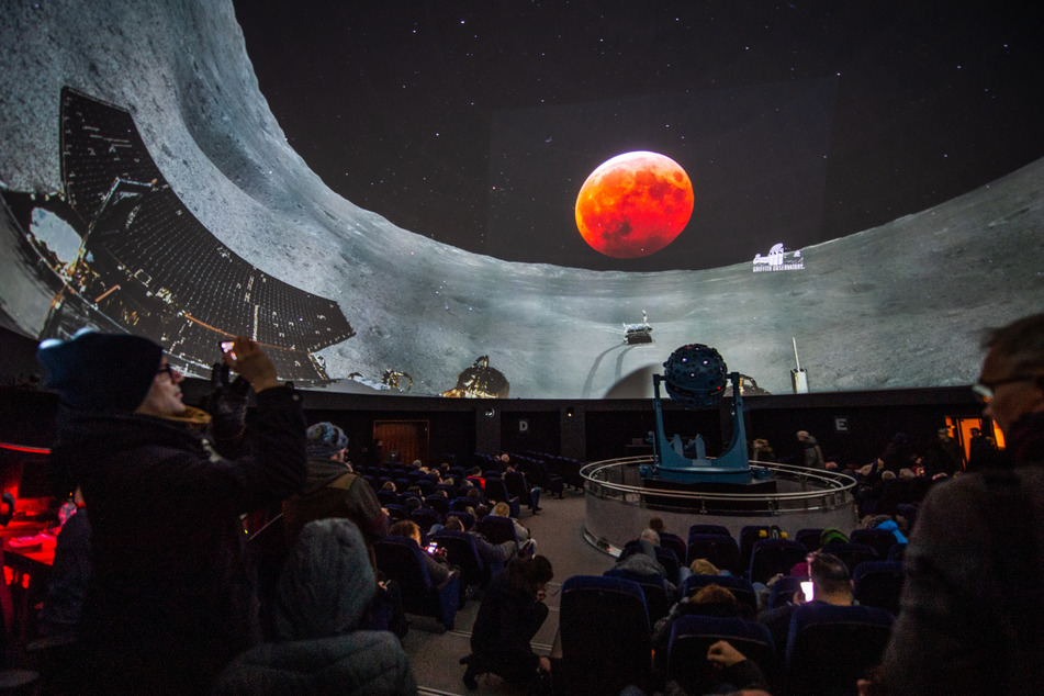 Besucher im Planetarium Bochum betrachten den Livestream der totalen Mondfinsternis mit dem sogenannten "Blutmond".