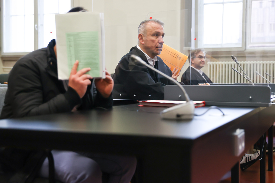 Die Angeklagten sitzen zwischen ihren Anwälten im Strafjustizgebäude.
