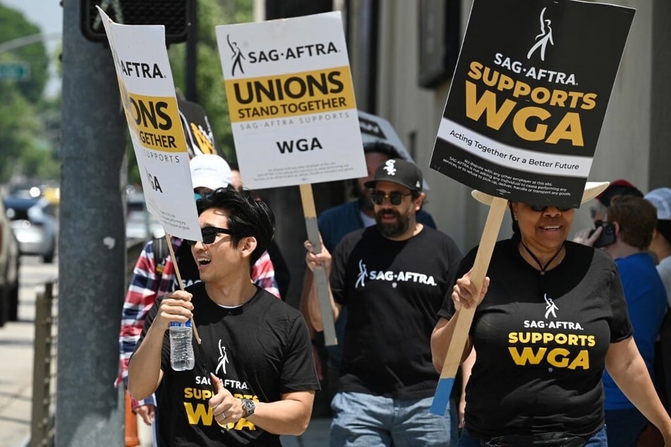 Hollywood writers and their supporters from the SAG AFTRA actors' union walk the picket line outside Warner Bros Studios in Burbank, California, on June 30, 2023.