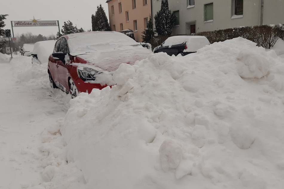 Riesige Schneeberge blockieren ein Auto in Leipzig-Holzhausen.