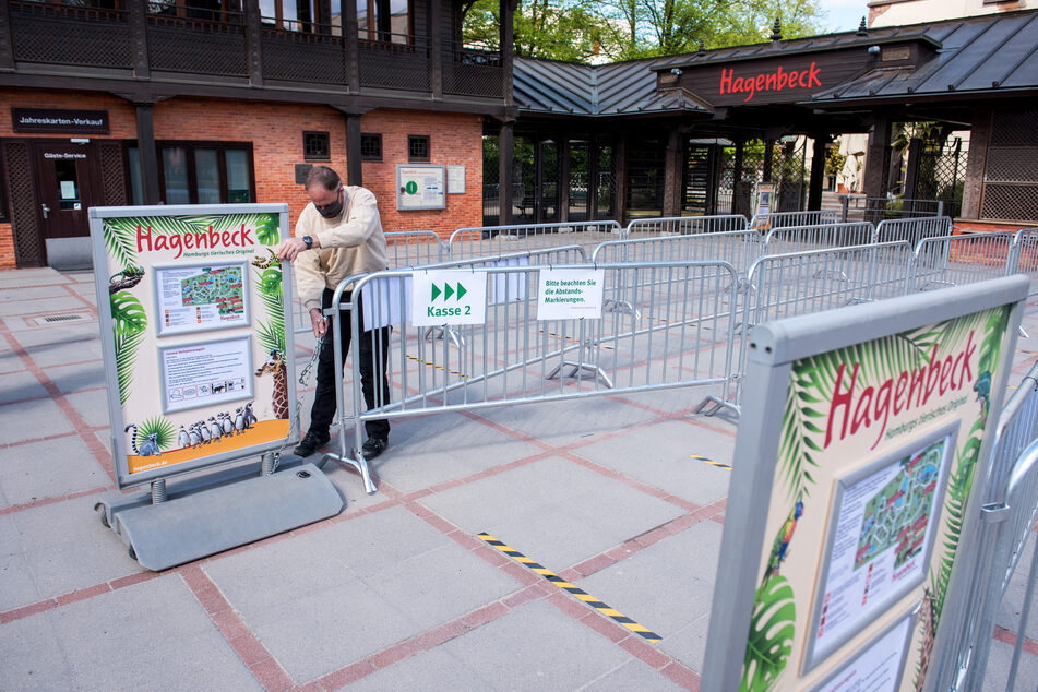 Ein Mitarbeiter stellt am Eingang von Hagenbecks Tierpark Schilder mit Hinweisen zu Verhaltensregeln auf.