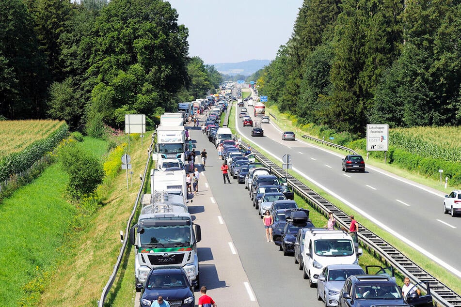 Die Autofahrer haben eine Rettungsgasse gebildet und stehen neben ihren Fahrzeugen auf der A8 bei Rohrdorf.