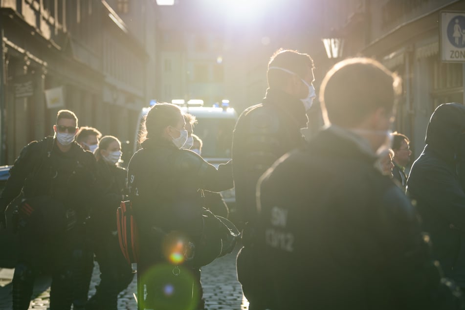 Polizisten stehen in Pirna am Rand einer Demonstration von Gegnern der Corona-Maßnahmen auf dem Marktplatz in einer Seitenstraße.