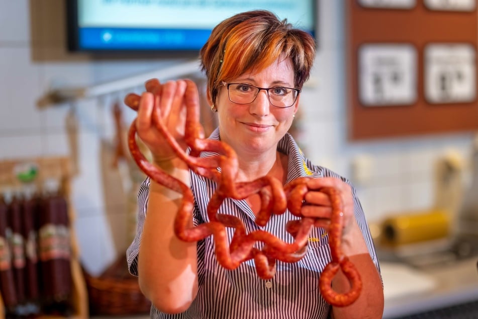 Verkäuferin Frau Hoffmann (45) mit Ringelwürsten an der Fleisch- und Frischetheke