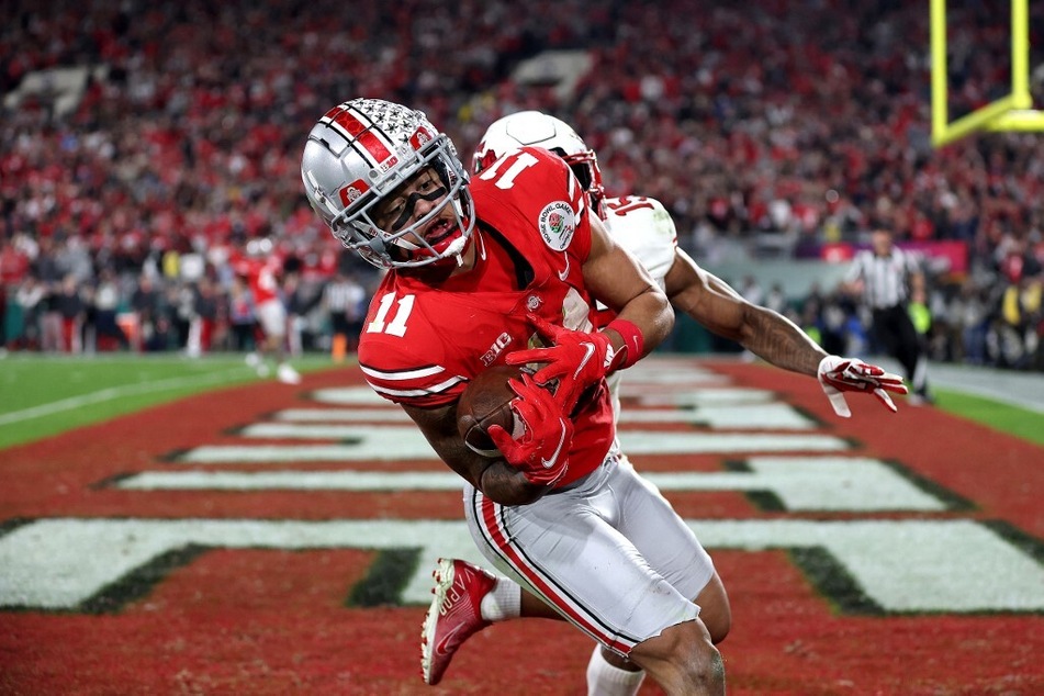 Jaxon Smith-Njigba of the Ohio State Buckeyes catches a touchdown pass against Malone Mataele of the Utah Utes to win the 2022 Rose Bowl Game.