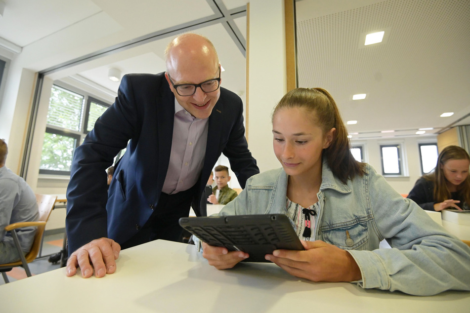 Bürgermeister Sven Schulze (48, SPD) betrachtet mit Sportgymnasium-Schülerin Nelly (13) eines der neuen Tablets.
