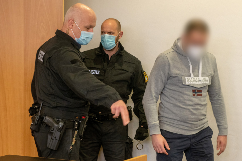 Der 34-Jährige wird von zwei Polizisten in den Gerichtssaal geführt.