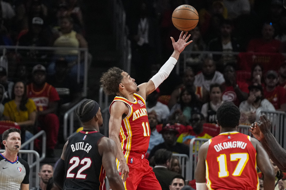 Atlanta Hawks guard Trae Young (c.) scored a basket behind Miami Heat forward Jimmy Butler (l.) during the first half of game three of the first round for the 2022 NBA playoffs at State Farm Arena on Friday. (Dale Zanine-USA TODAY Sports)