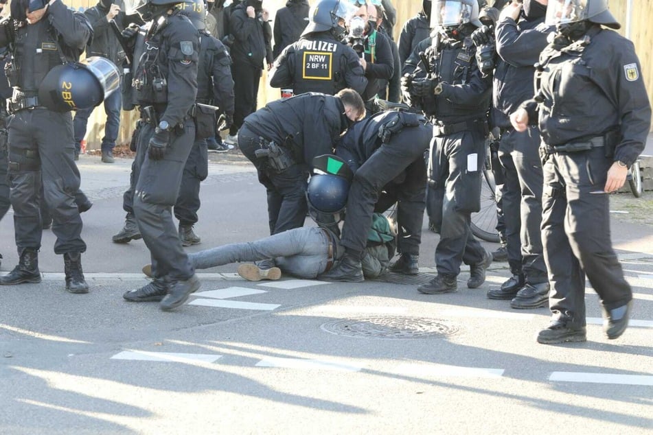 Ein Demonstrant wird von Polizisten zu Boden gerungen.