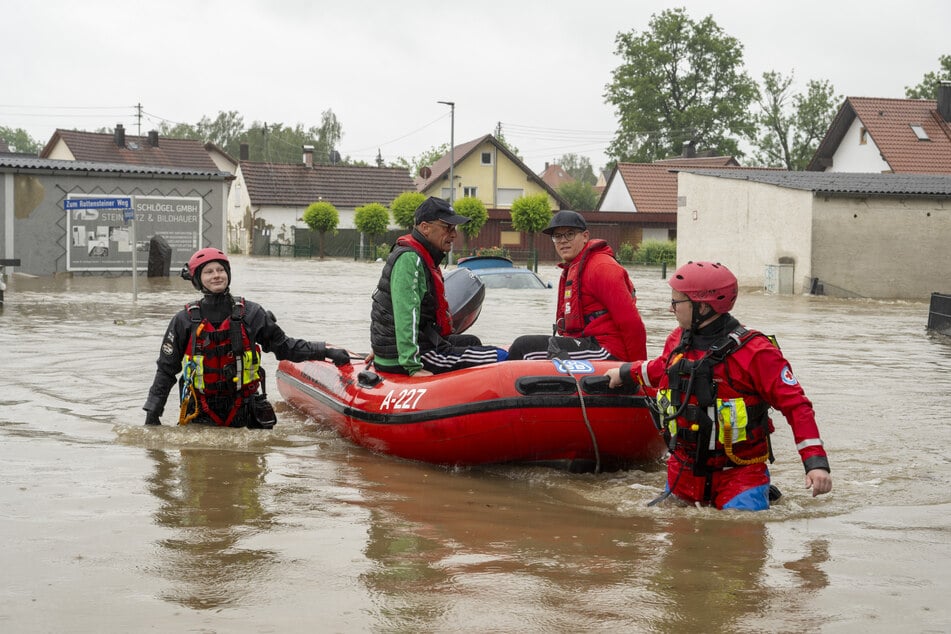 Wasserretter bergen Bewohner aus überschwemmten Häusern.