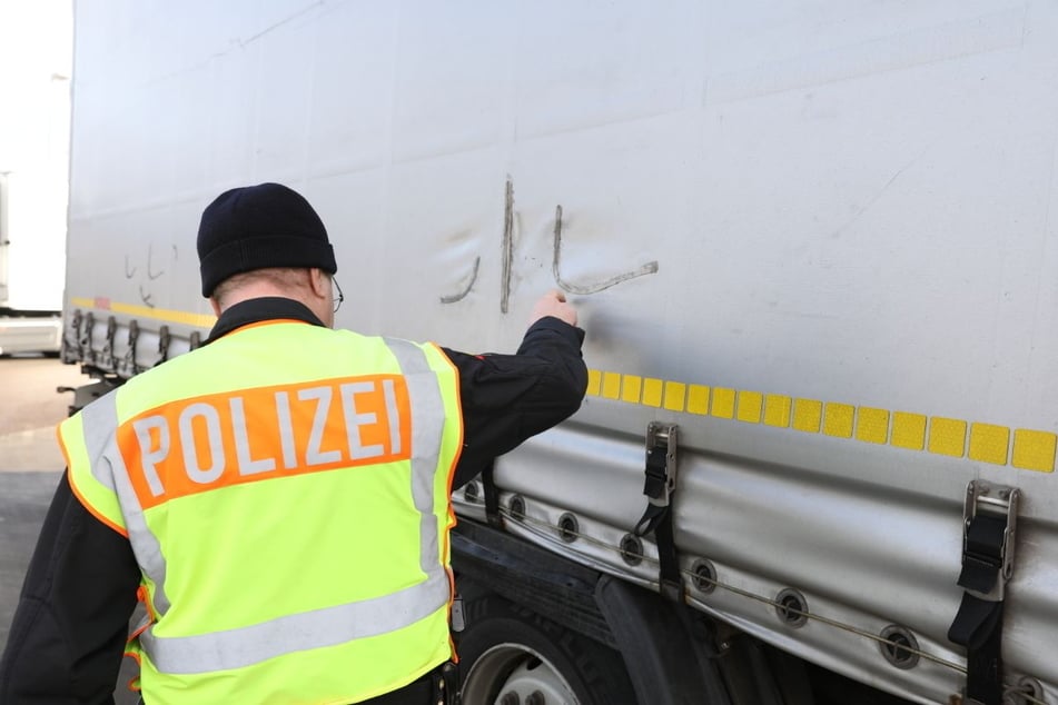 Ein Polizist bei der Spurensicherung an einer aufgeschlitzten Plane. Immer wieder suchen dreiste Diebe Laster auf Raststätten heim.