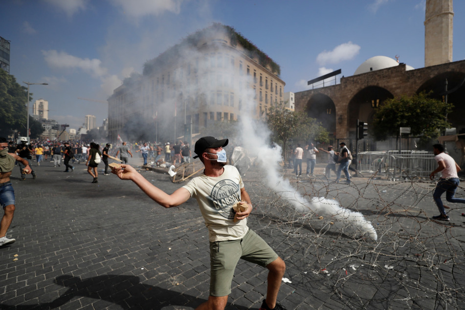 Ein Protestierender wirft Steine in Richtung der Sicherheitskräfte während eines Protests gegen die politischen Eliten und die Regierung nach der tödlichen Explosion im Hafen von Beirut.