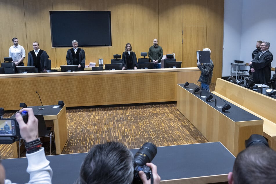 Im Schwurgerichtssaal des Landgerichts steht ein Mann vor der Strafkammer unter Vorsitz von Michael Eberle (3.v.l) und den Richtern Martin Neumann und Katja Baues und den Verteidigern Michael Weiss (r) und Jörg Seubert.