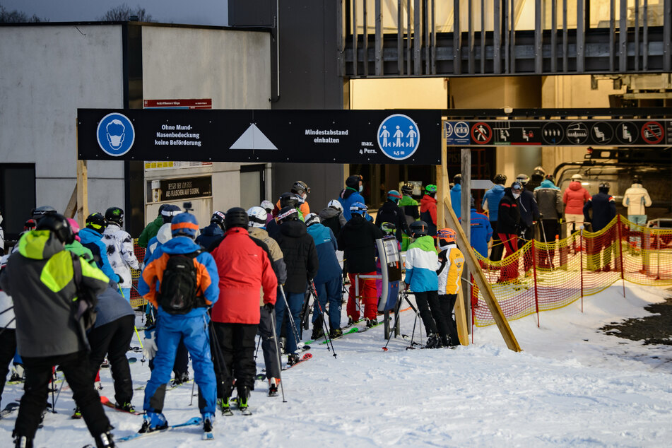 Wintersportler stehen beim Flutlichtskifahren an der Talstation Schlange.