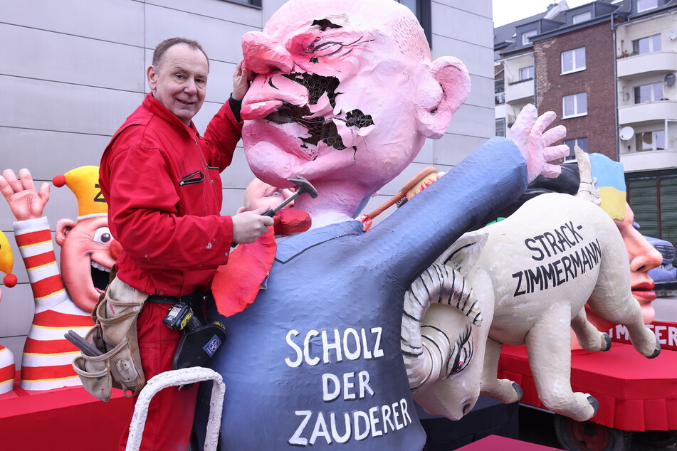 Wagenbauer Jacques Tilly (59) reißt die Pappmaché-Figur von Olaf Scholz ein.
