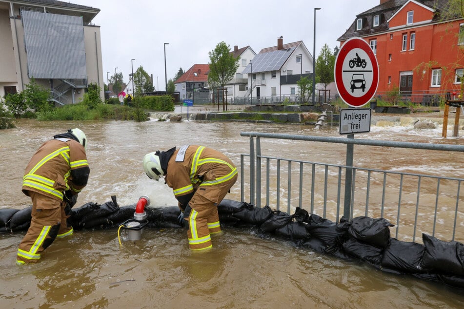 Einsatzkräfte der Feuerwehr stapeln in Ochsenhausen Sandsäcke als Schutzwall auf.