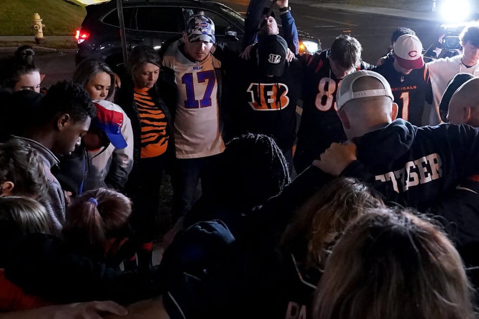 In den Farben getrennt, in der Sache vereint: Fans der Cincinnati Bengals und der Buffalo Bills beten vor dem Krankenhaus für den auf dem Spielfeld wiederbelebten Spieler Damar Hamlin (24).
