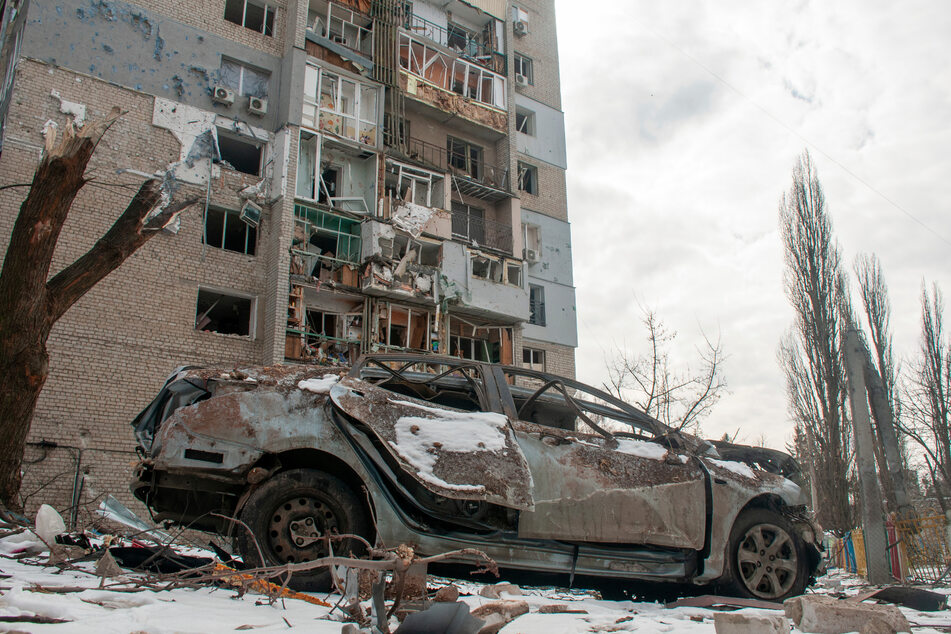 So schlimm sieht es mittlerweile in Charkiw aus. Ein zerstörtes Auto steht vor einem durch Beschuss zerstörtem Wohnhaus.