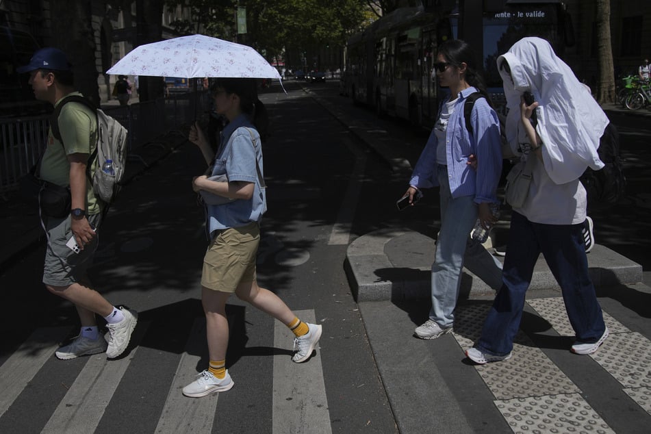 In Frankreich sind zwei Menschen aufgrund der Hitze ums Leben gekommen. Das Foto zeigt Touristen in Paris, die sich vor der Wärme schützen.