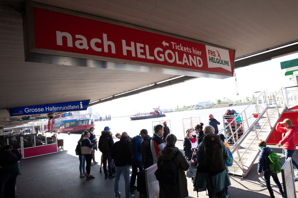 Fahrgäste stehen vor der High-Speed Fähre Halunder Jet an den Landungsbrücken.