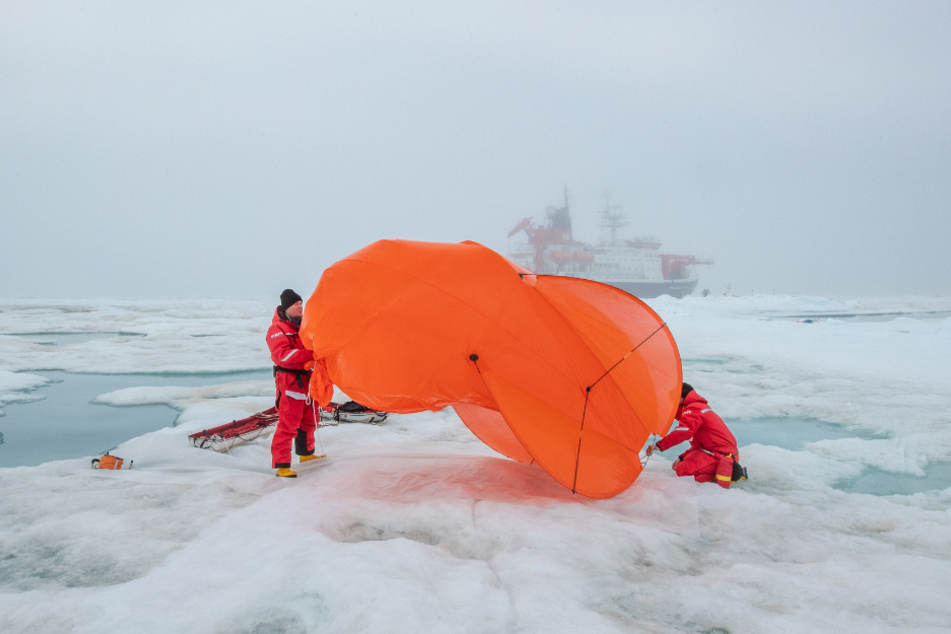 Mitarbeiter der Expedition packen einen Fesselballon zusammen.