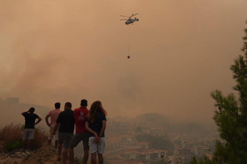 Aus sicherer Entfernung beobachten Menschen den Löscheinsatz in Alanya.