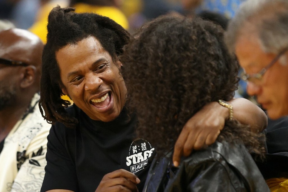 Jay-Z going in for a hug as the cameras spotlight him and his daughter.