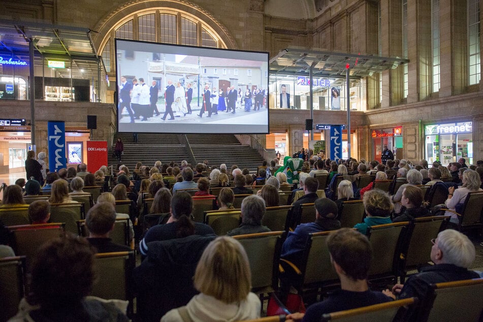 Besucher des Festivals schauen "Bei uns heißt sie Hanka" von Grit Lemke auf einer Leinwand im Leipziger Hauptbahnhof. (Archiv)