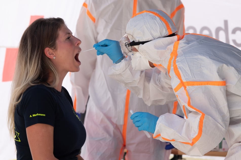 Antonia Werthmann (l), THW-Helferin, lässt sich von einer Mitarbeiterin des Deutschen Roten Kreuzes (DRK) in Schutzkleidung anlässlich eines Pressetermins in einer mobilen Covid-19-Beprobungsstation mit einem Abstrichstäbchen testen.