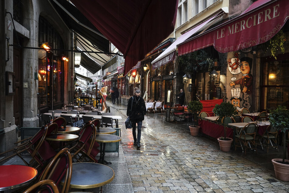 Eine Frau geht an leeren Restaurants im Zentrum von Lyon vorbei.