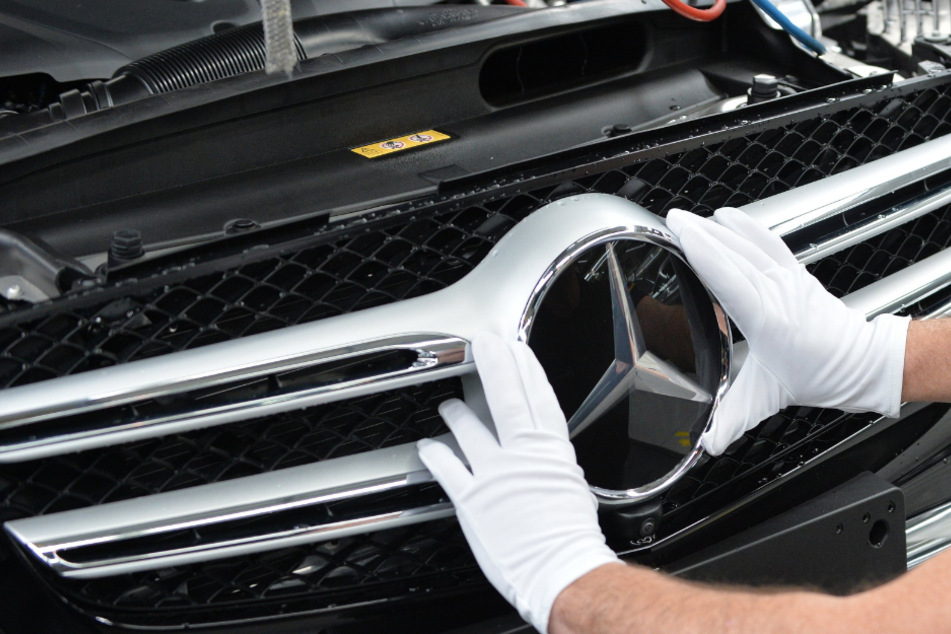 Ein Mitarbeiter von Mercedes-Benz bringt im Werk den Stern an einem Auto der C-Klasse an.