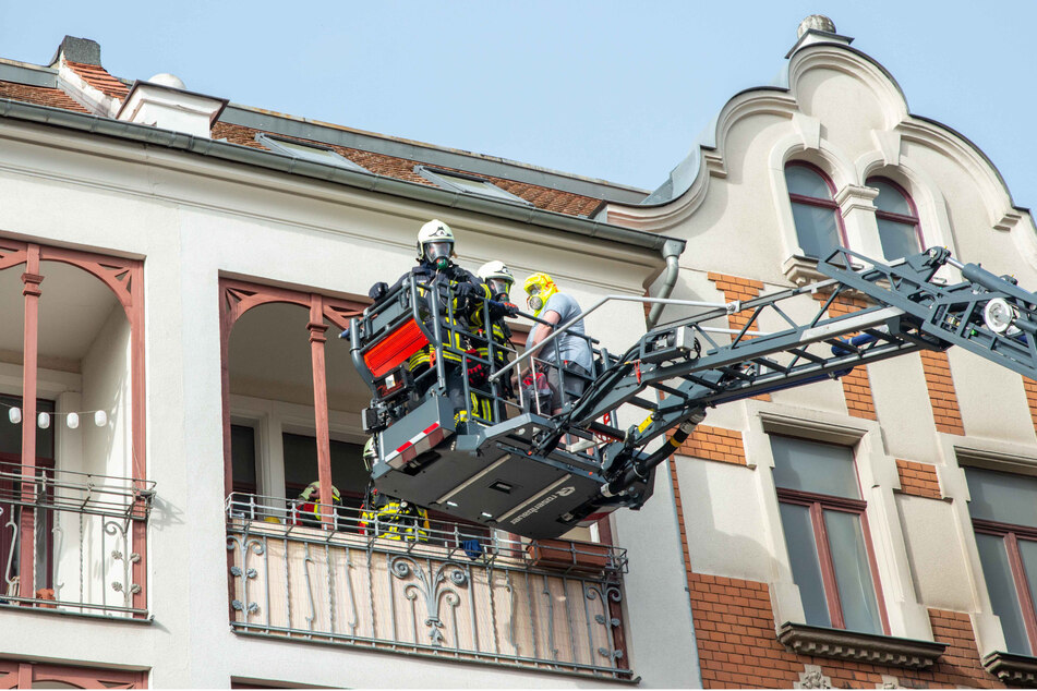 Die Einsatzkräfte der Feuerwehr bringen einen Bewohner über eine Drehleiter in Sicherheit.