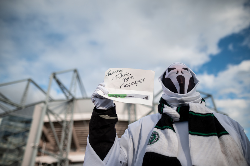 Ein Fan in einem Geisterkostüm steht vor dem Stadion mit einem Zettel auf dem «Tausche Tickets gegen Klopapier» steht.