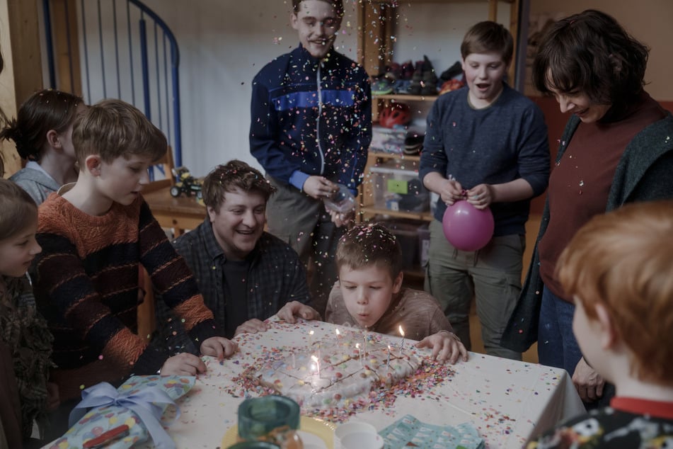 Umringt von seinen Freunden und den Heimerziehern pustet Ronny die Kerzen auf seiner Geburtstagstorte aus.