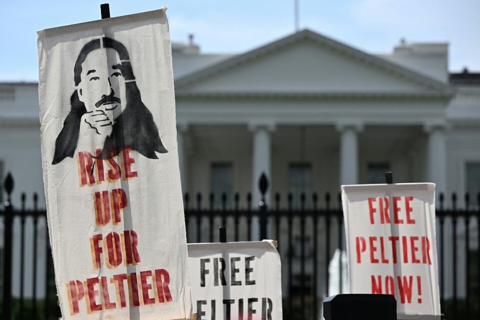 Indigenous activists raise signs reading "Free Peltier Now!" in front of the White House in Washington DC.