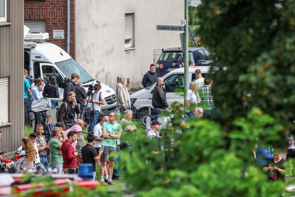 Schaulustige stehen, teilweise mit Kameras, am Straßenrand, um sich die Sprengung des Hochhauses "Weißer Riese" anzuschauen.