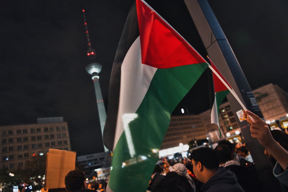 Teilnehmer an einer Pro-Palästina Kundgebung stehen auf dem Alexanderplatz.