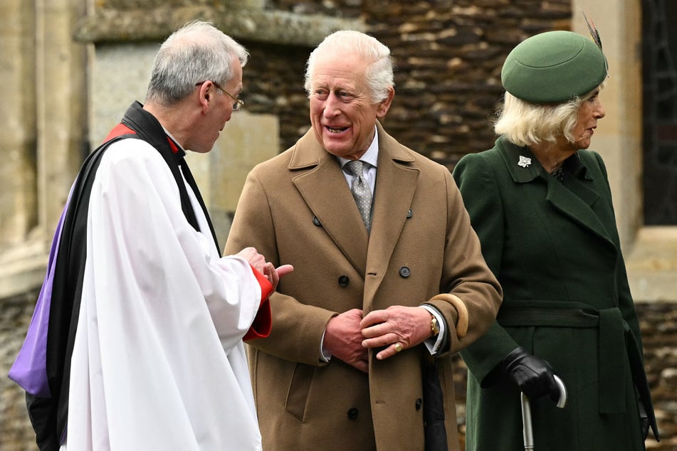 Britain's King Charles III (c.) talks with Reverend Canon Paul Williams after attending the Royal Family's traditional Christmas Day service at St Mary Magdalene Church in Sandringham, Norfolk, eastern England, on Wednesday.