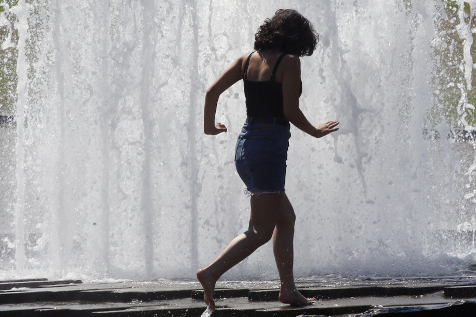 Eine junge Frau sucht etwas Abkühlung an einem City-Brunnen im Lustgarten.