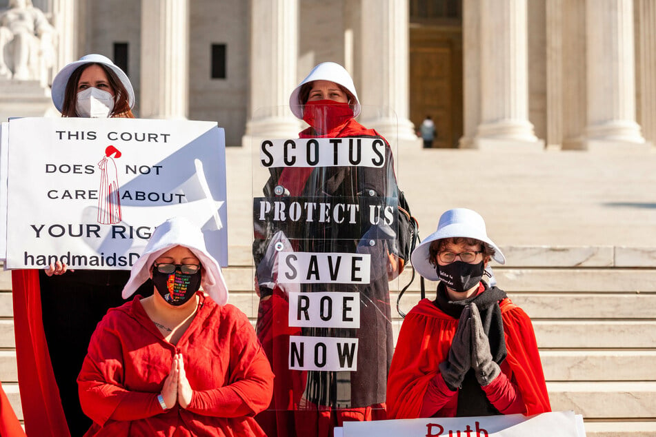 Demonstrators dressed as handmaids from The Handmaid's Tale protest for reproductive rights in front of the Supreme Court.