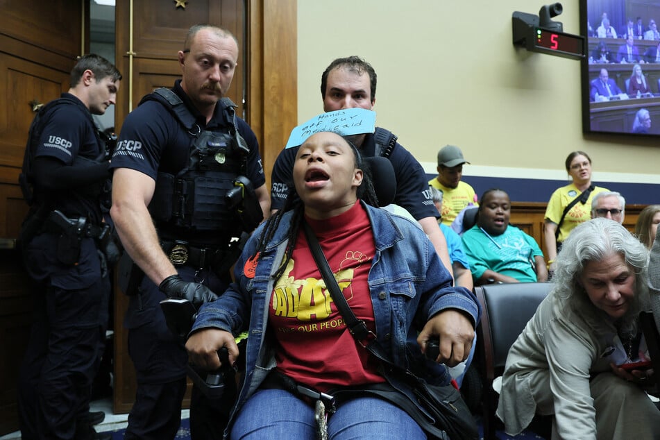 Capitol Police remove a protester in a wheelchair from the House Energy and Commerce Committee hearing room on May 13, 2025.