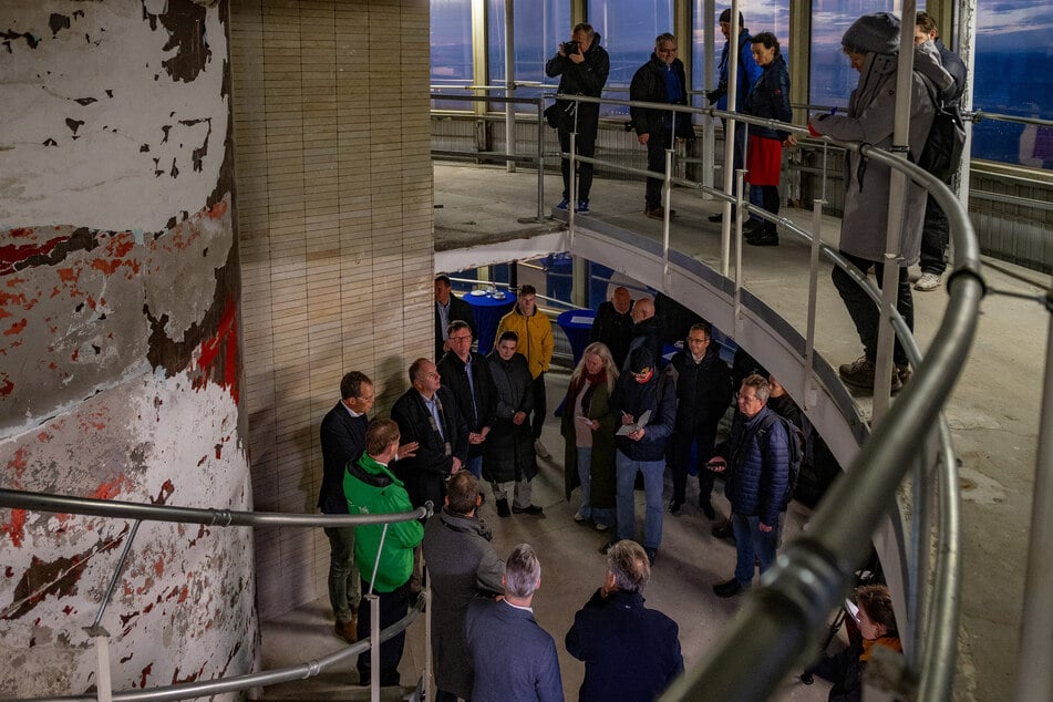 Die Verantwortlichen stellen im Innenren des früheren zweistöckigen Restaurants ihre Pläne vor, darunter Ministerpräsident Michael Kretschmer (50, CDU, grüne Jacke).
