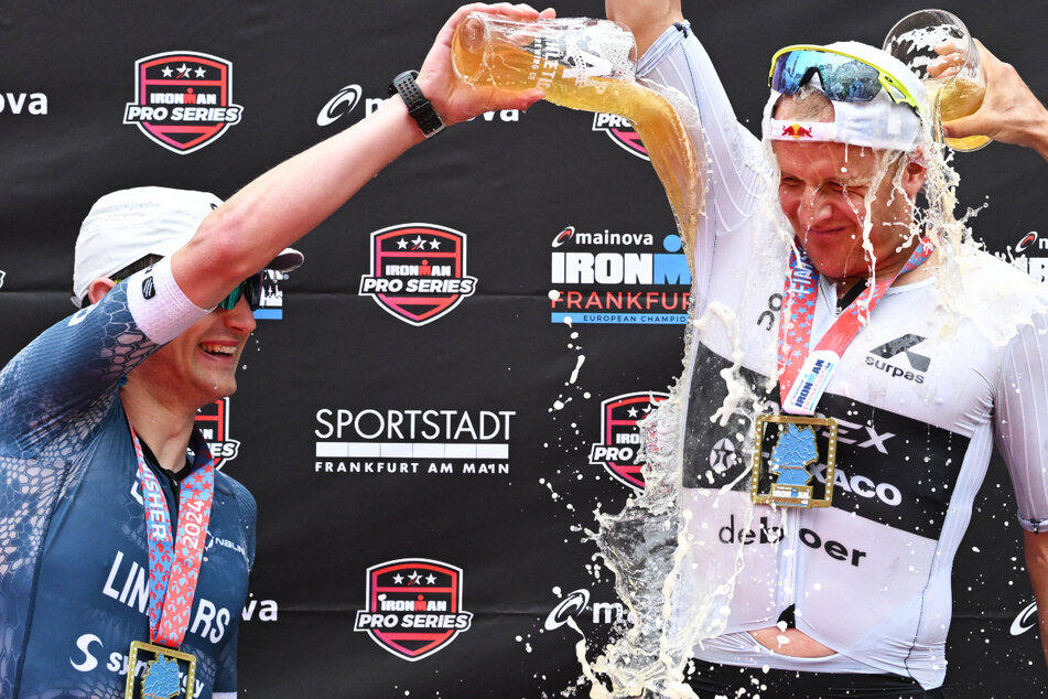 Ironman-Sieger Kristian Blummenfelt (l) bekommt bei der Siegerehrung eine Bierdusche verpasst.